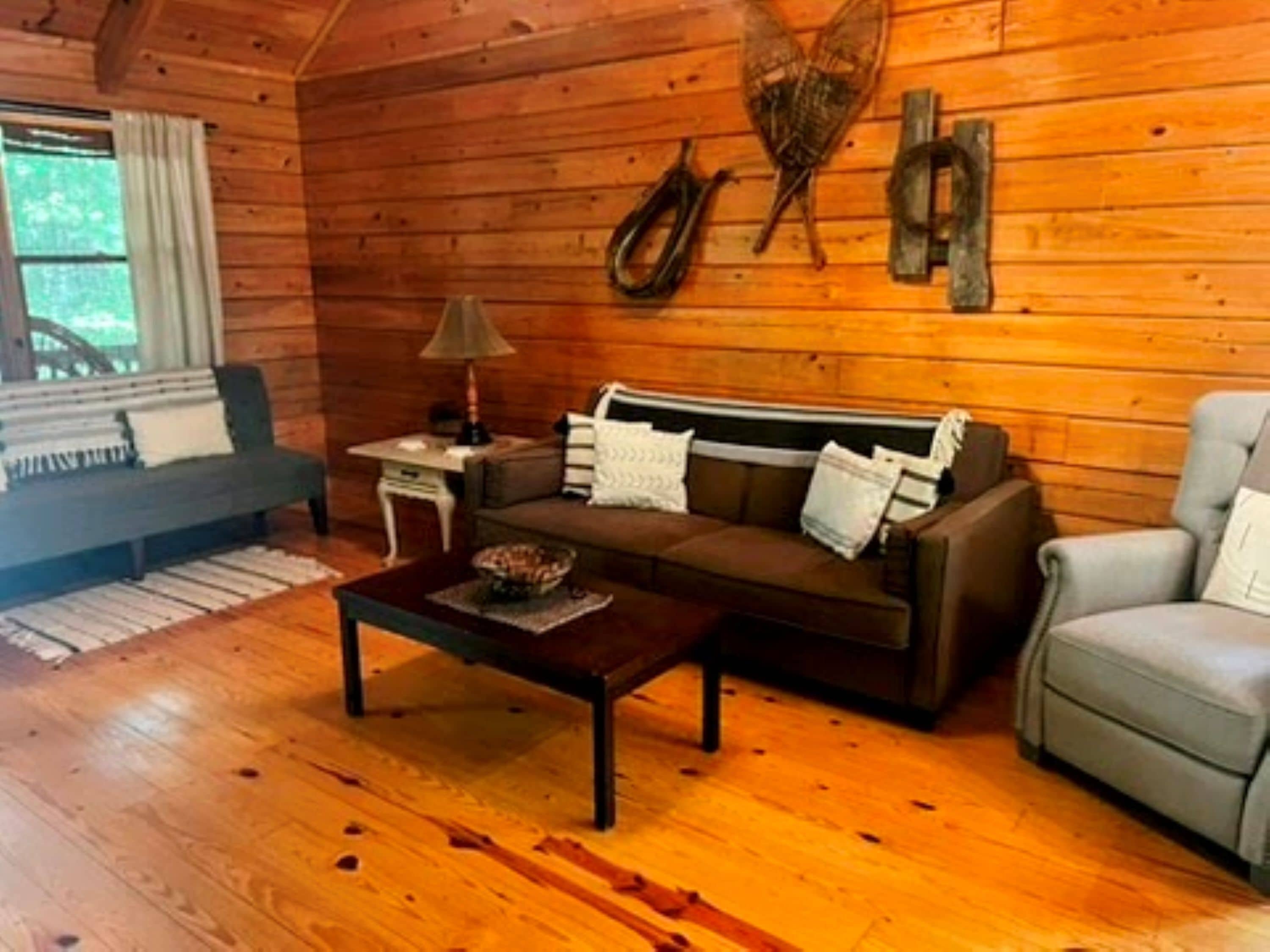 A cozy wooden cabin interior with a sofa, armchair, and a small table.