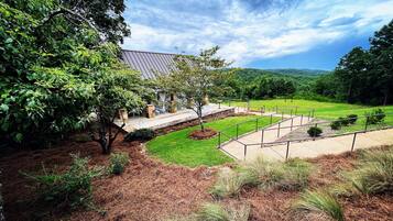 A landscaped outdoor area with a building, pathways, and a grassy field.