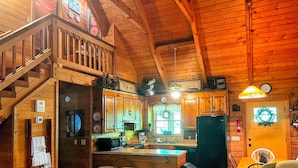 A wooden cabin interior with a kitchen, dining area, and a staircase. - Mountain Top Inn and Resort (Warm Springs)