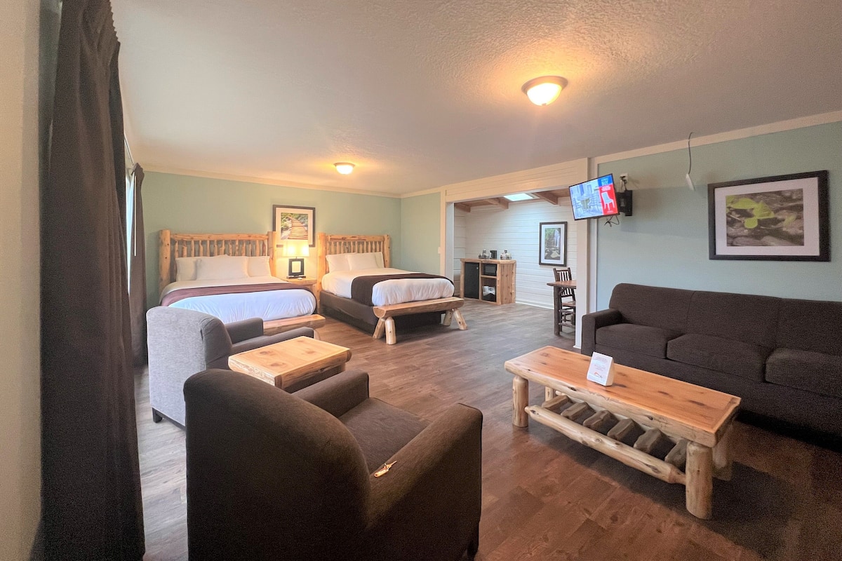 A room with two beds, a sofa, a TV, and a wooden coffee table.