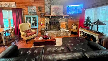 Una sala de estar acogedora con chimenea de piedra, un televisor montado en la pared y un comedor con muebles de madera.