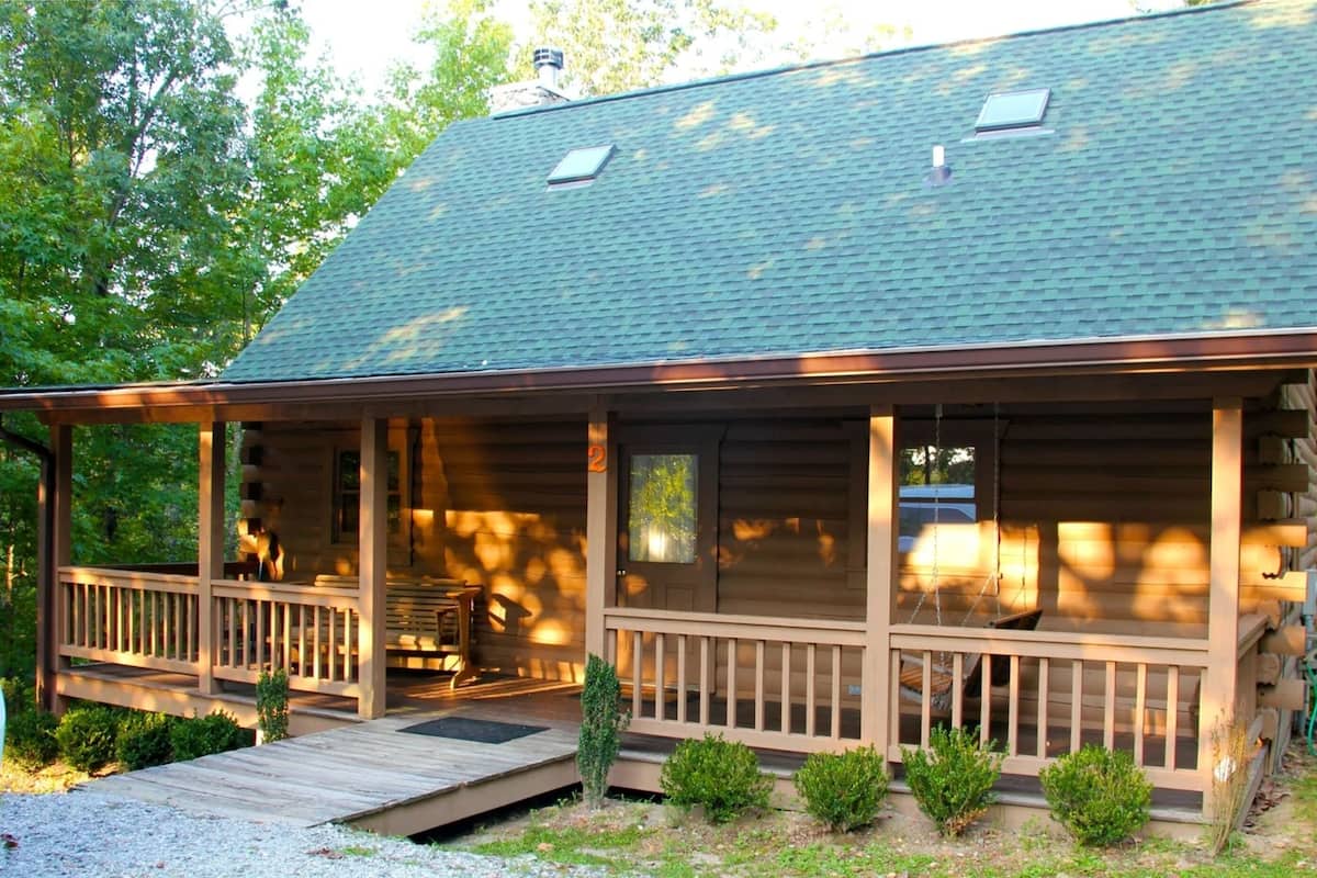 A cabin with a porch, a small deck, and a covered outdoor seating area.