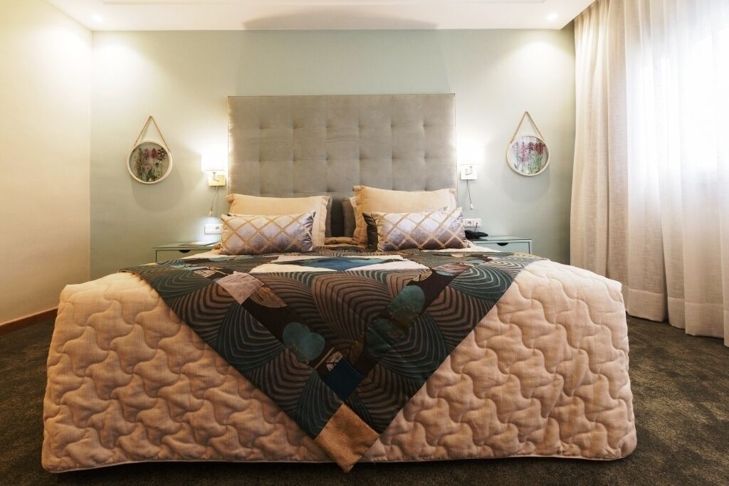 Una cama grande con cubrecolchón acolchado, dos mesitas de noche y lámparas de pared.