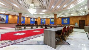 A conference room with a red carpet, wooden panel walls, and a chandelier. - Hotel Rabat (Rabat)