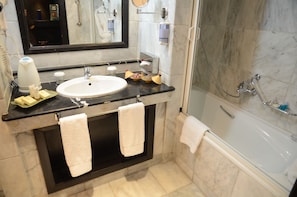 A modern bathroom with a marble sink, a black countertop, two white towels, a mirror, and a glass-enclosed shower.