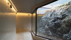 Een modern interieur met een stenen muur en een groot raam met uitzicht op een rotsachtig landschap.