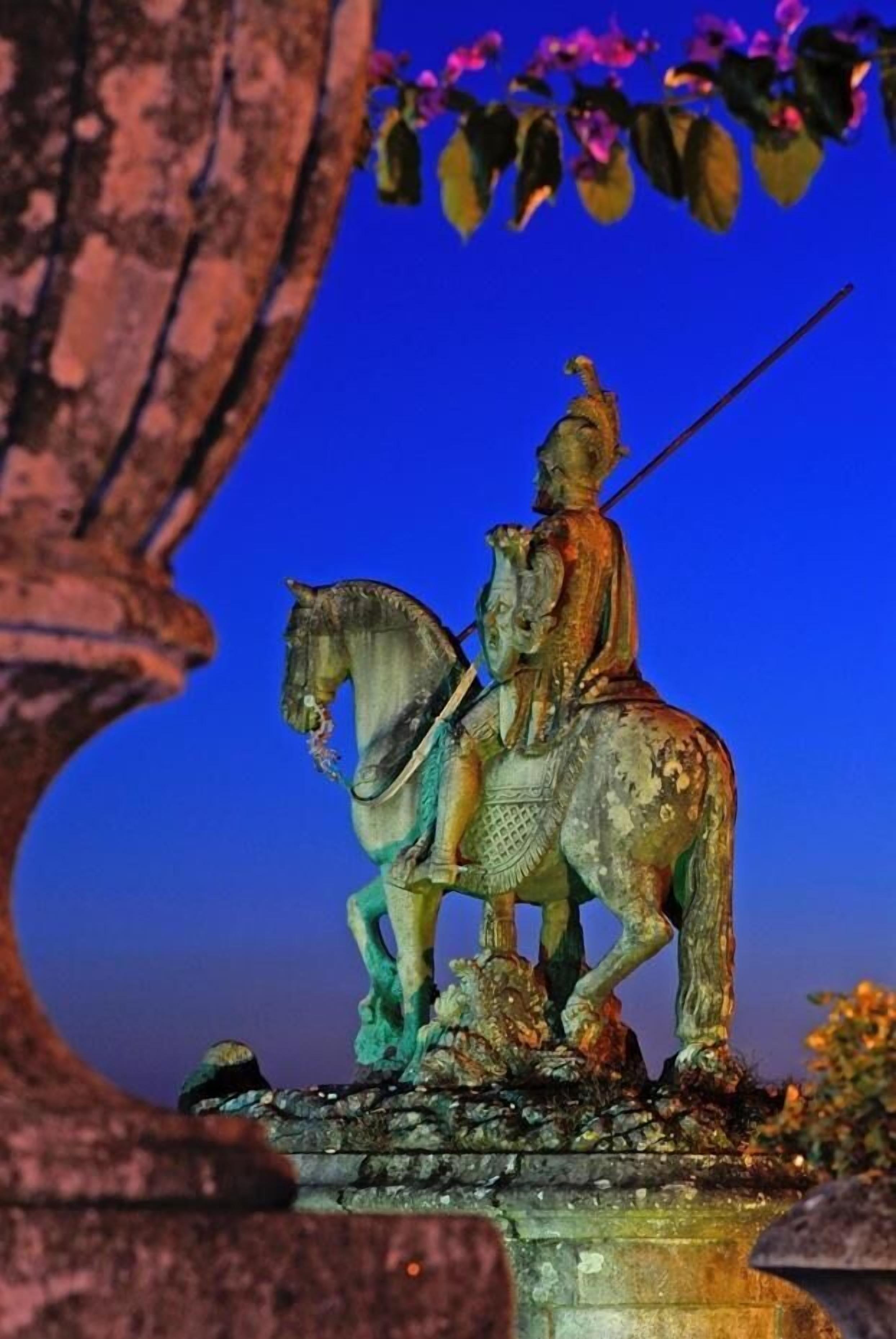 A statue of a figure on horseback, set against a twilight sky.