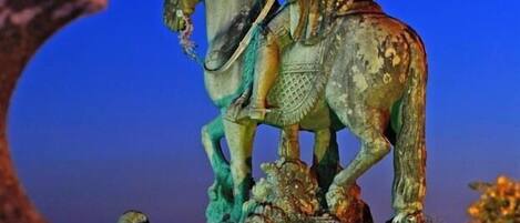 Una estatua de una figura a caballo, con un cielo crepuscular de fondo.