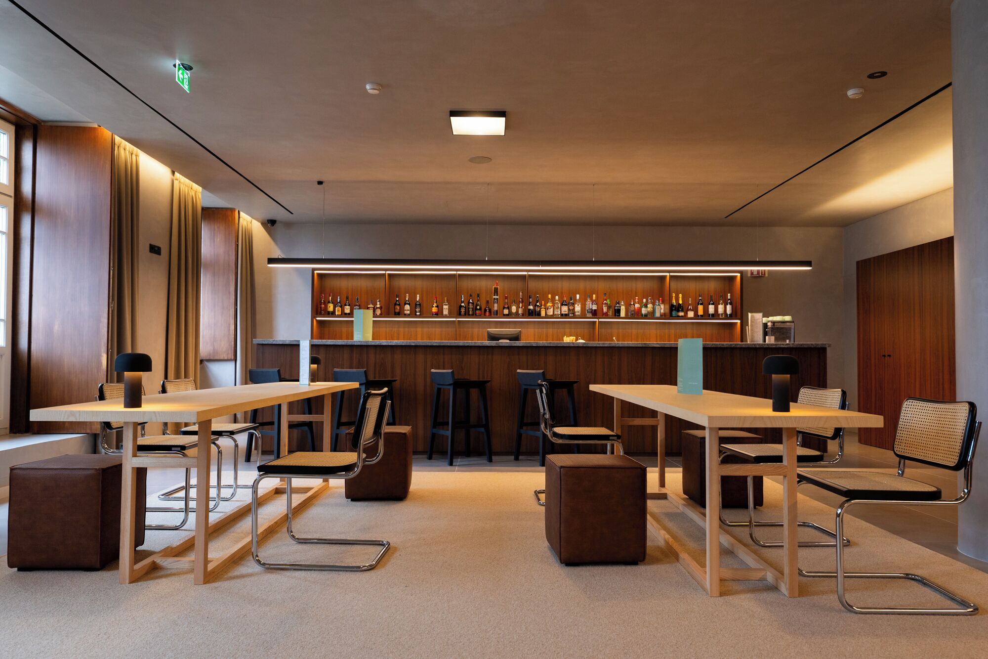 Un bar moderne doté d’un long comptoir, de nombreux tabourets et d’une grande variété de bouteilles.