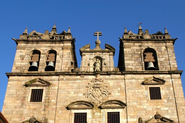 A historic building with two bell towers, a central dome, and a cross at the top.