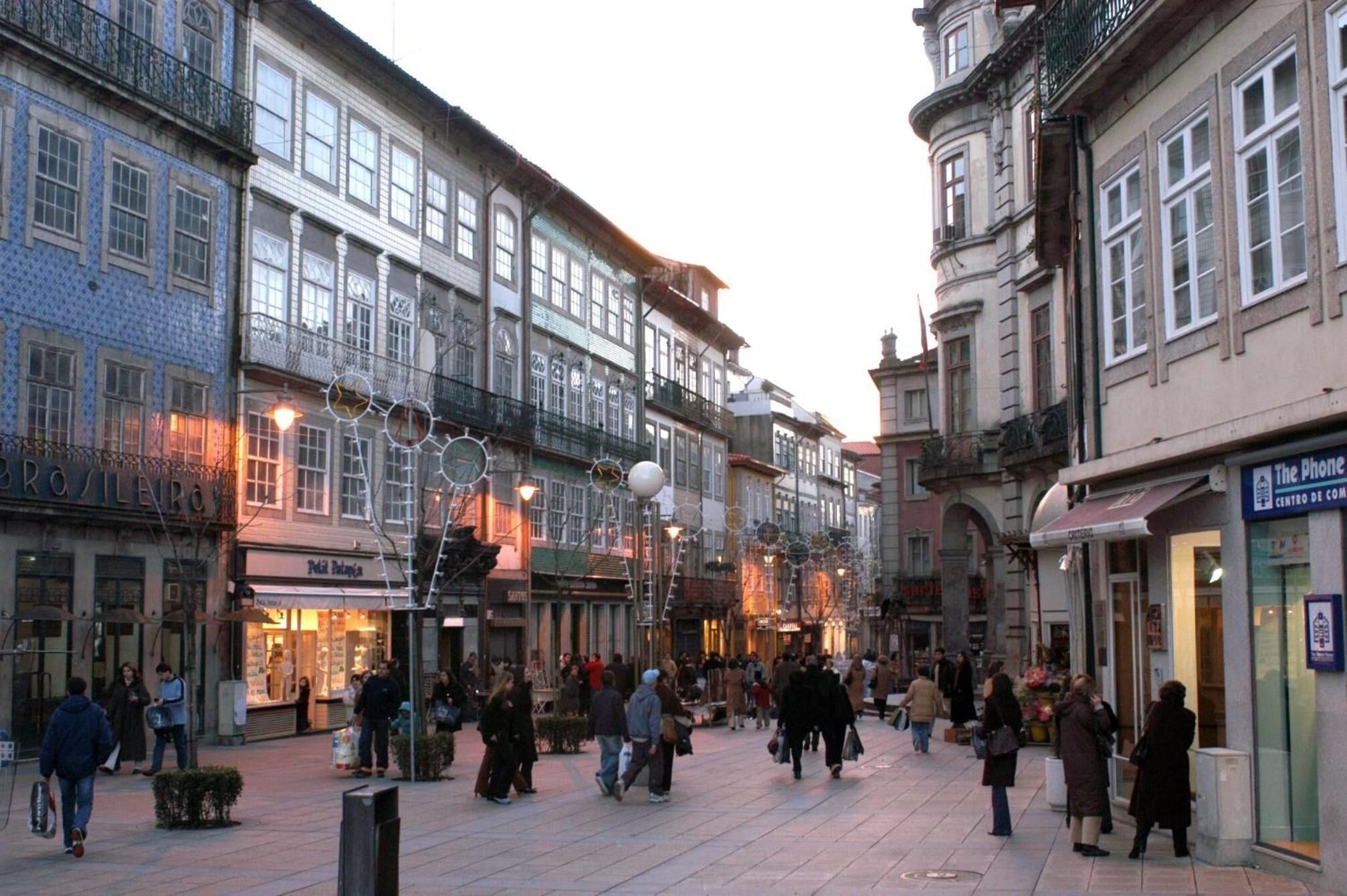 A busy urban street with historic buildings, shops, and pedestrians.