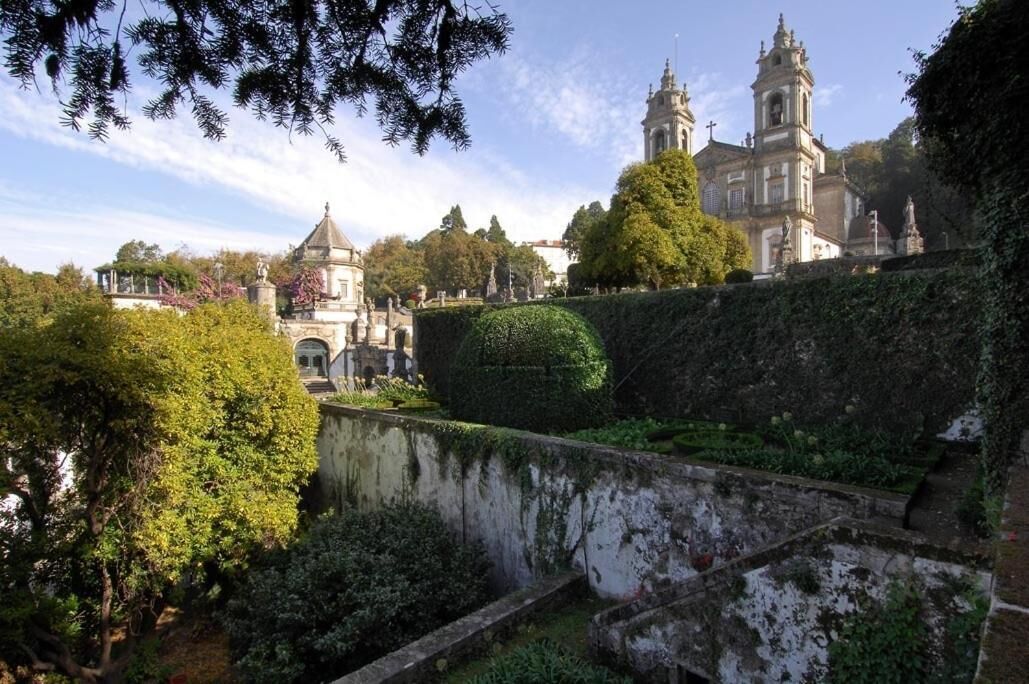 A historic building with a large dome and bell towers, surrounded by lush greenery and a well-maintained garden.