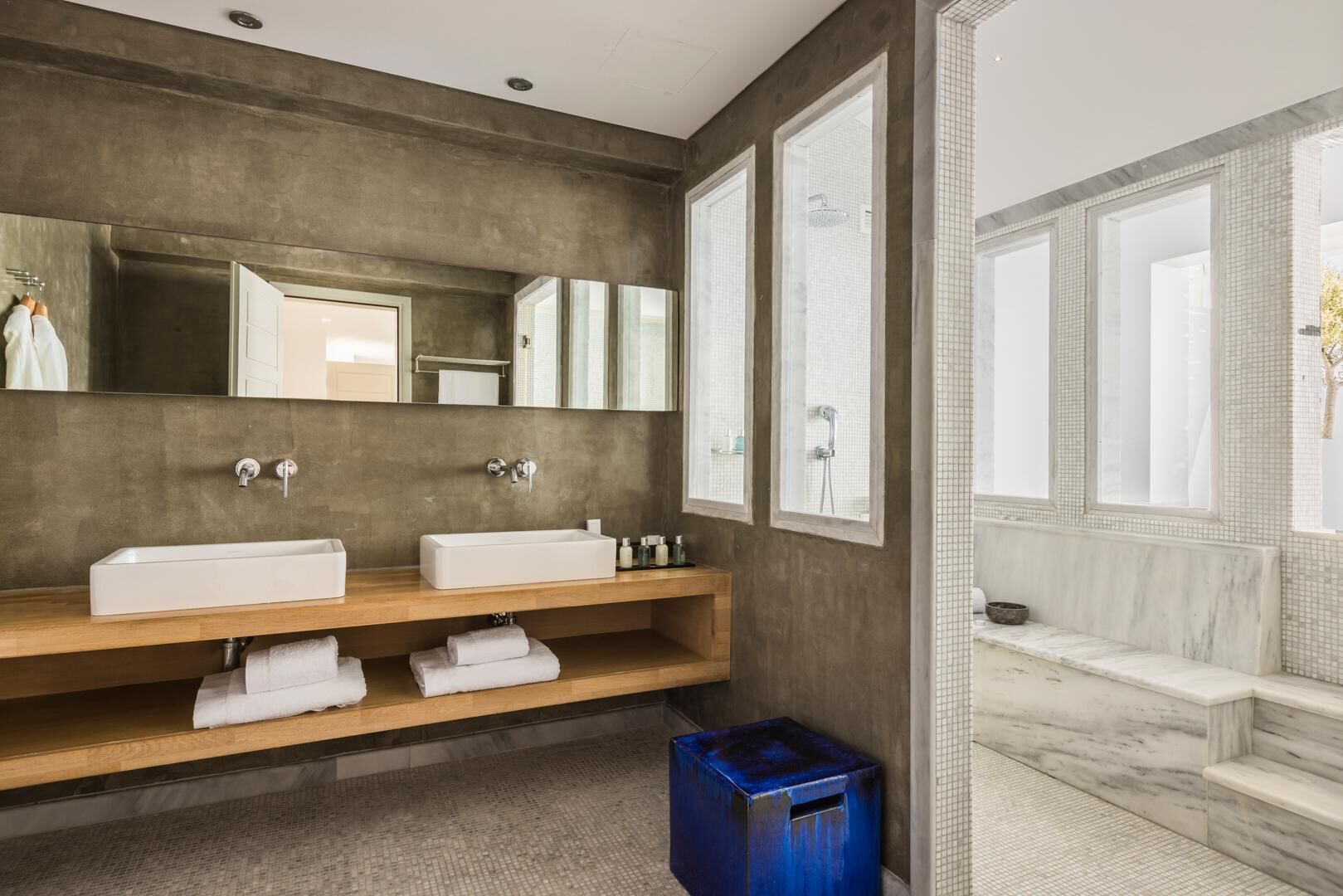 A modern bathroom with two sinks, a large mirror, and a marble bathtub.