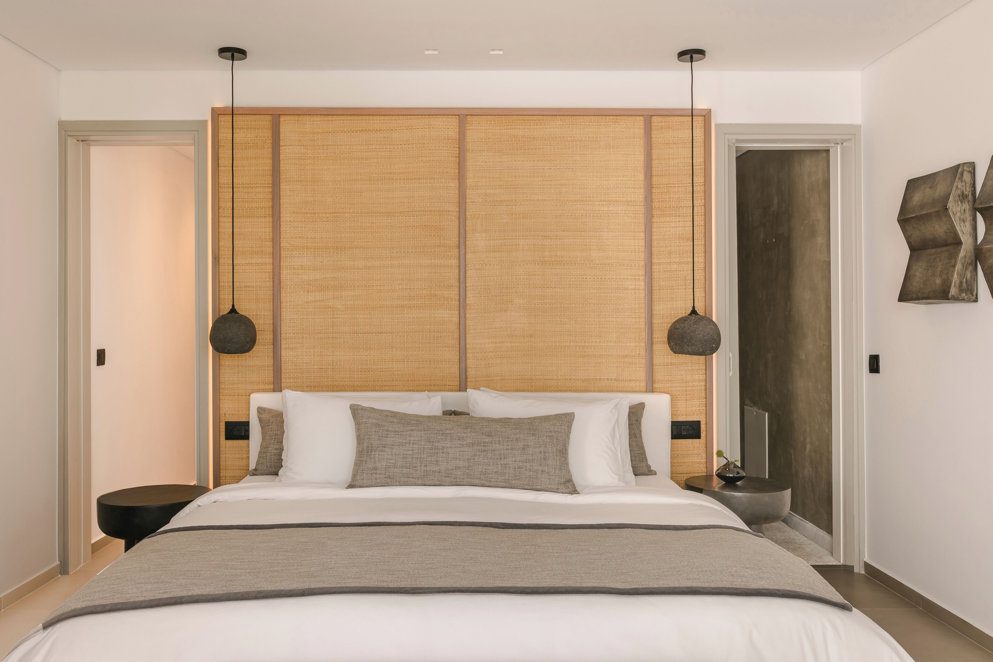 Une chambre moderne avec un grand lit, une tête de lit en bois et deux lampes suspendues.