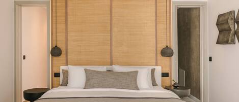 Une chambre moderne avec un grand lit, une tête de lit en bois et deux lampes suspendues.