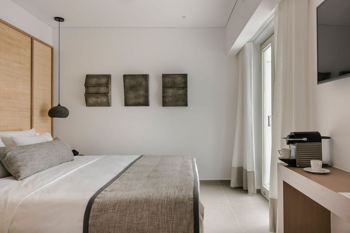 A modern bedroom with a bed, bedside table, and a view of the outdoors.