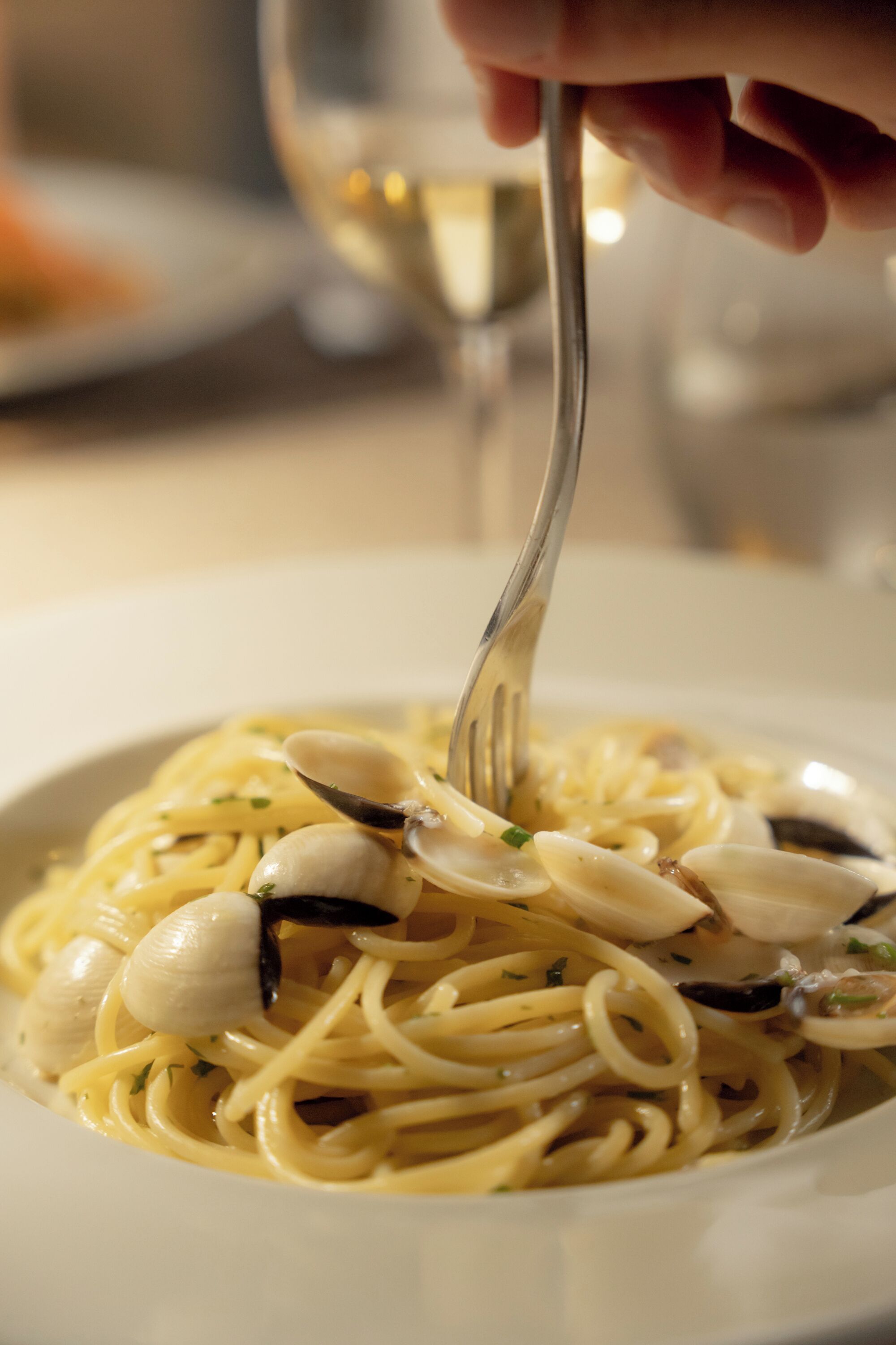 Un plato de pasta con almejas, servido con un tenedor.
