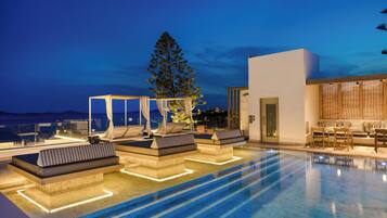 Een buitenzwembad, parasols bij het zwembad en ligstoelen