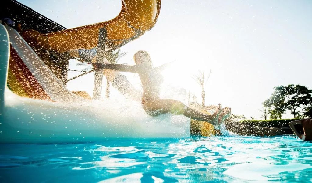 A water slide over a pool with clear water and a sunny sky.