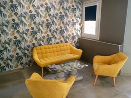 Una habitación con un sofá amarillo, un sillón a juego y una mesa de centro de vidrio.