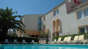 Una piscina al aire libre de temporada, sillones reclinables de piscina