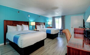 A hotel room with two beds, a desk, a chair, and a television. - The Majestic Regency Resort (Wells)