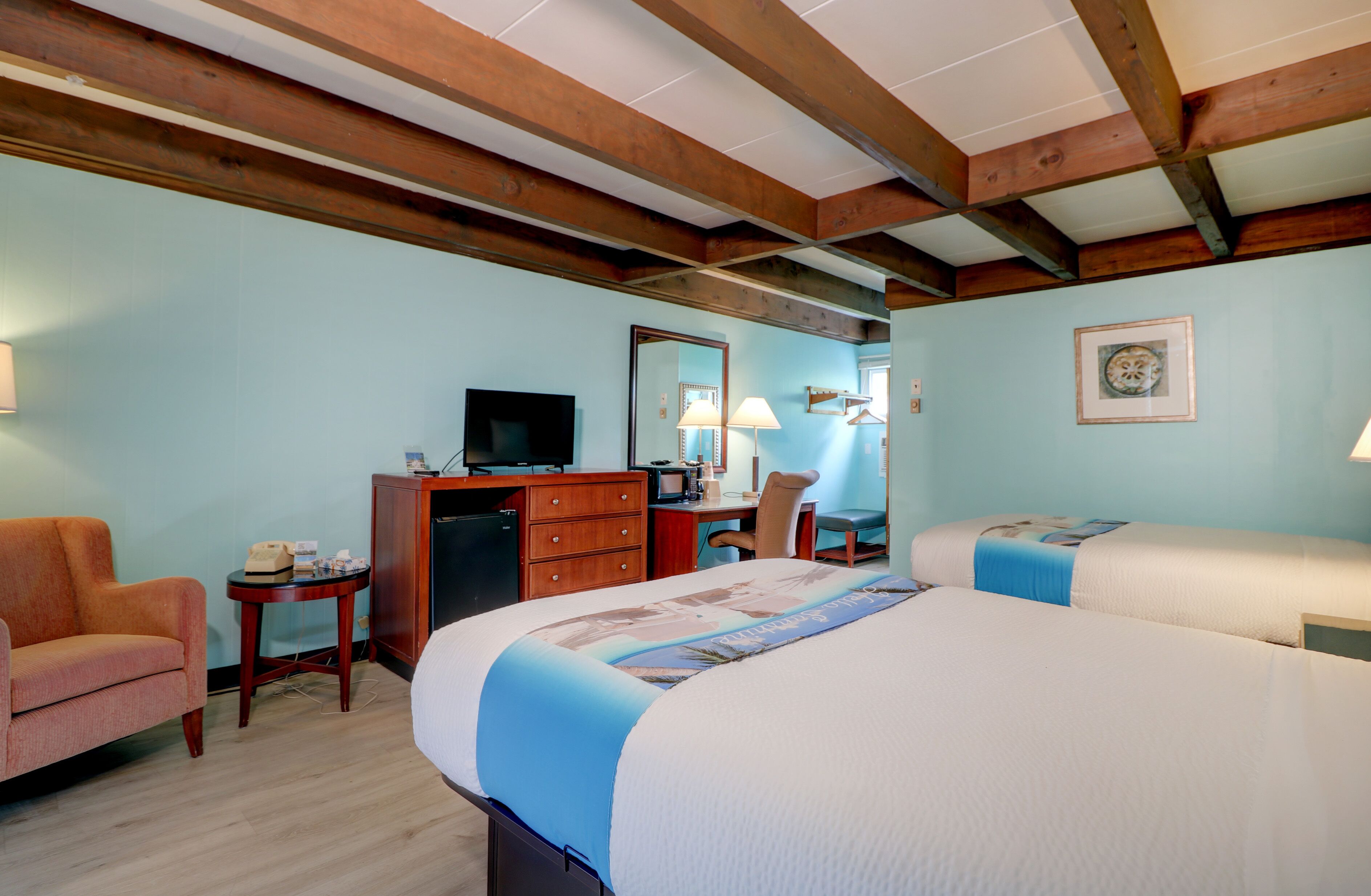 Una habitación de hotel con una cama grande, un escritorio con ordenador, una televisión y una silla.
