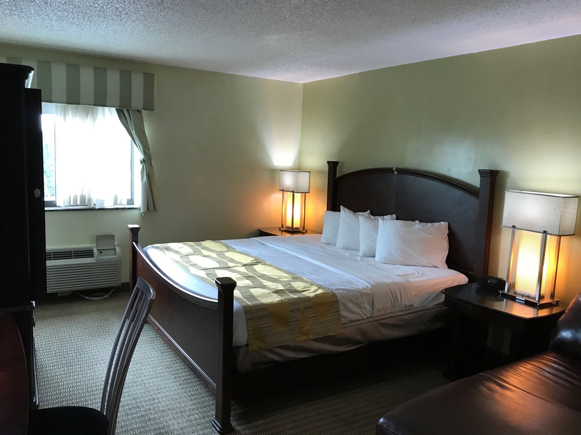A hotel room with a bed, bedside lamps, a desk, and a chair.