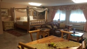 A room with a four-poster bed, a wooden table with chairs, a sofa, and a small coffee table.