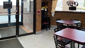 A restaurant interior with a brick wall, framed pictures, and a 'Thank You' sign.