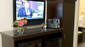 A hotel reception area with a television displaying a news program, a vase with flowers, and a water dispenser. - North Bay Inn (San Rafael)