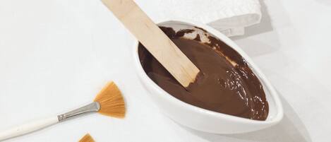 A white bowl with a wooden stick and two paintbrushes on a white surface.