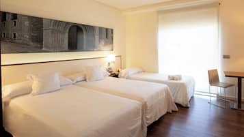 A hotel room with two beds, a desk, a chair, and a large painting on the wall.
