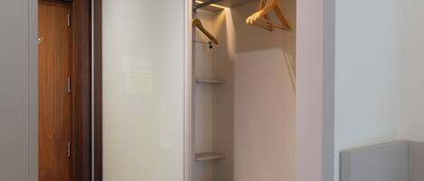 Vestidor con puerta corredera, piso de madera e integrado un banco con espacio de almacenamiento.