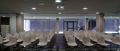 A conference room with rows of chairs, a projector, and large windows.