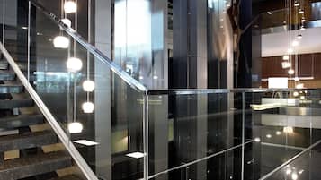 Un interior moderno con una escalera de cristal, suelos reflectantes e iluminación contemporánea.