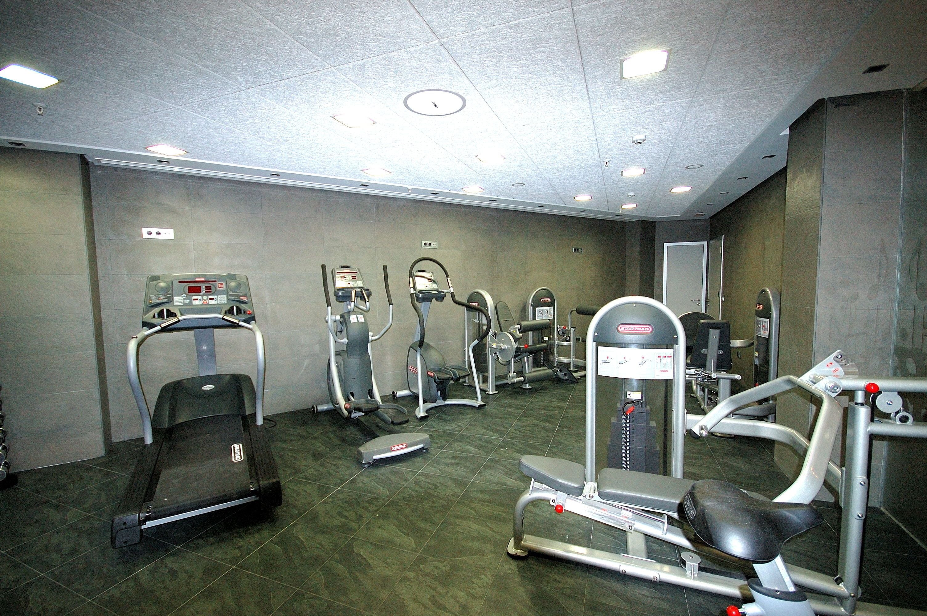 A gym with various exercise equipment including treadmills, elliptical machines, and weight machines.