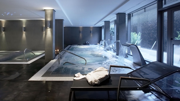 Un spa moderno en el interior, con jacuzzi, zona de estar y grandes ventanales.