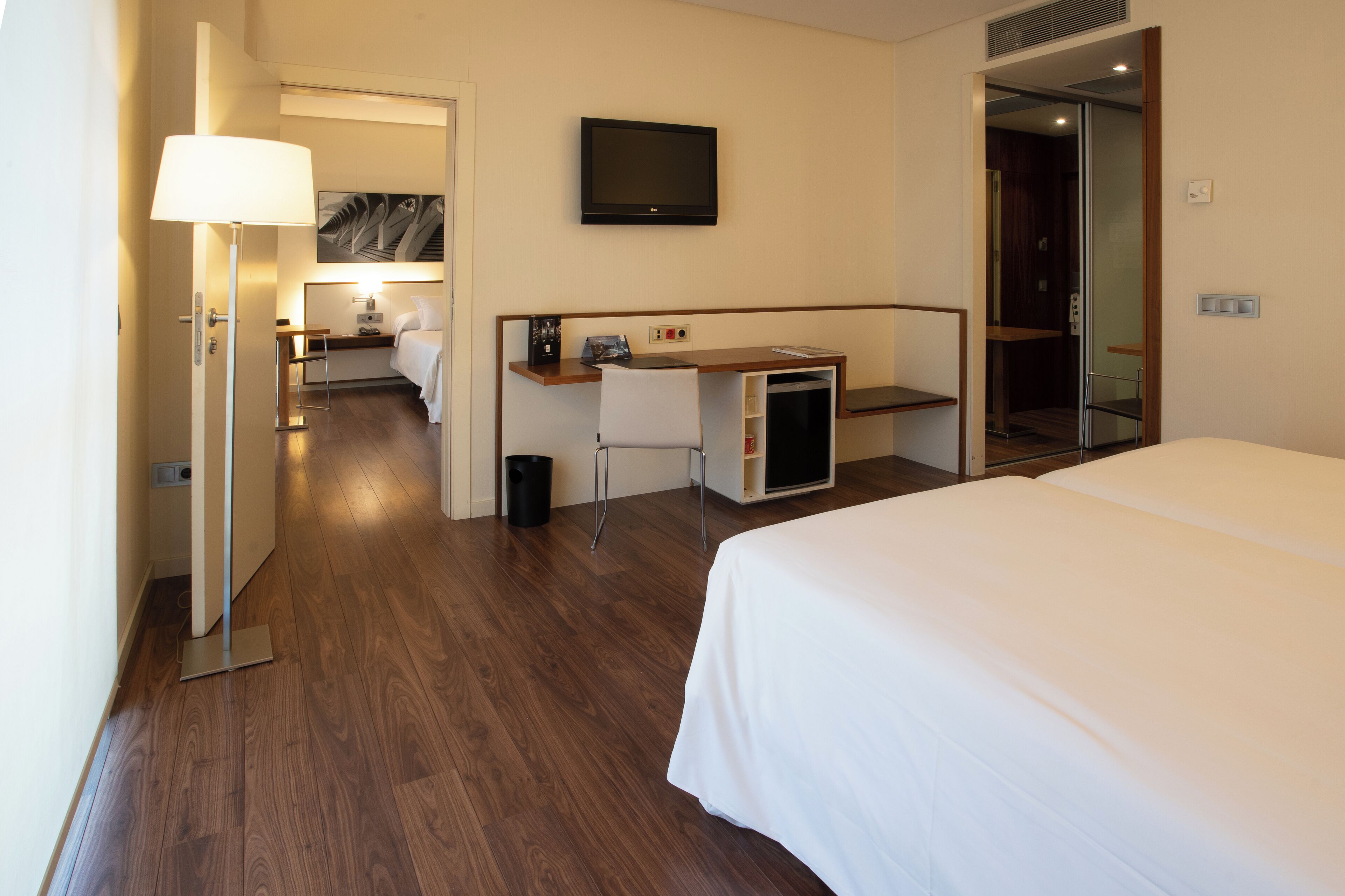 Une chambre d’hôtel équipée d’un lit, d’un bureau, d’une chaise, d’une télévision et d’une petite kitchenette.