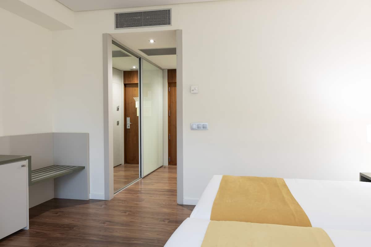 Una habitación de hotel con una cama, un escritorio y un armario.