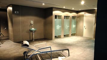 Un baño moderno con un banco, un lavamanos y puertas de vidrio esmerilado con diseños de copos de nieve.