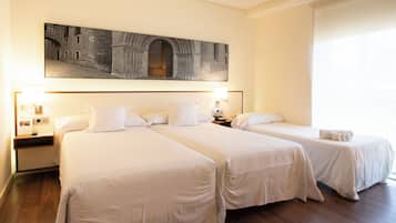 Ein Hotelzimmer mit zwei Betten, einem großen gerahmten Bild an der Wand und einem Fenster mit Jalousien.