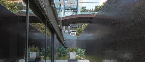 An outdoor lounge area with a glass wall, a pool, and a view of a high-rise building.