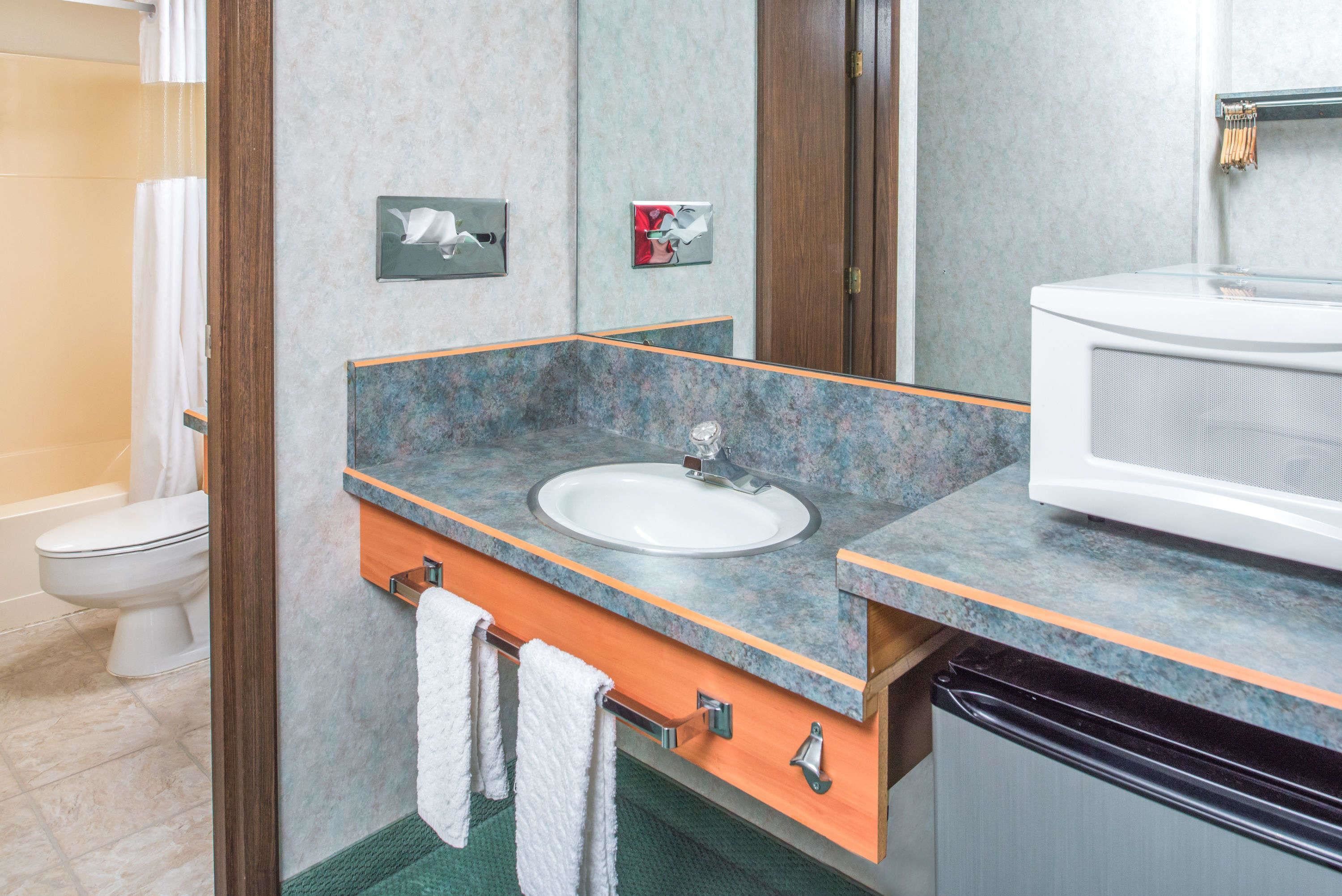 A bathroom with a sink, mirror, and towel rack.