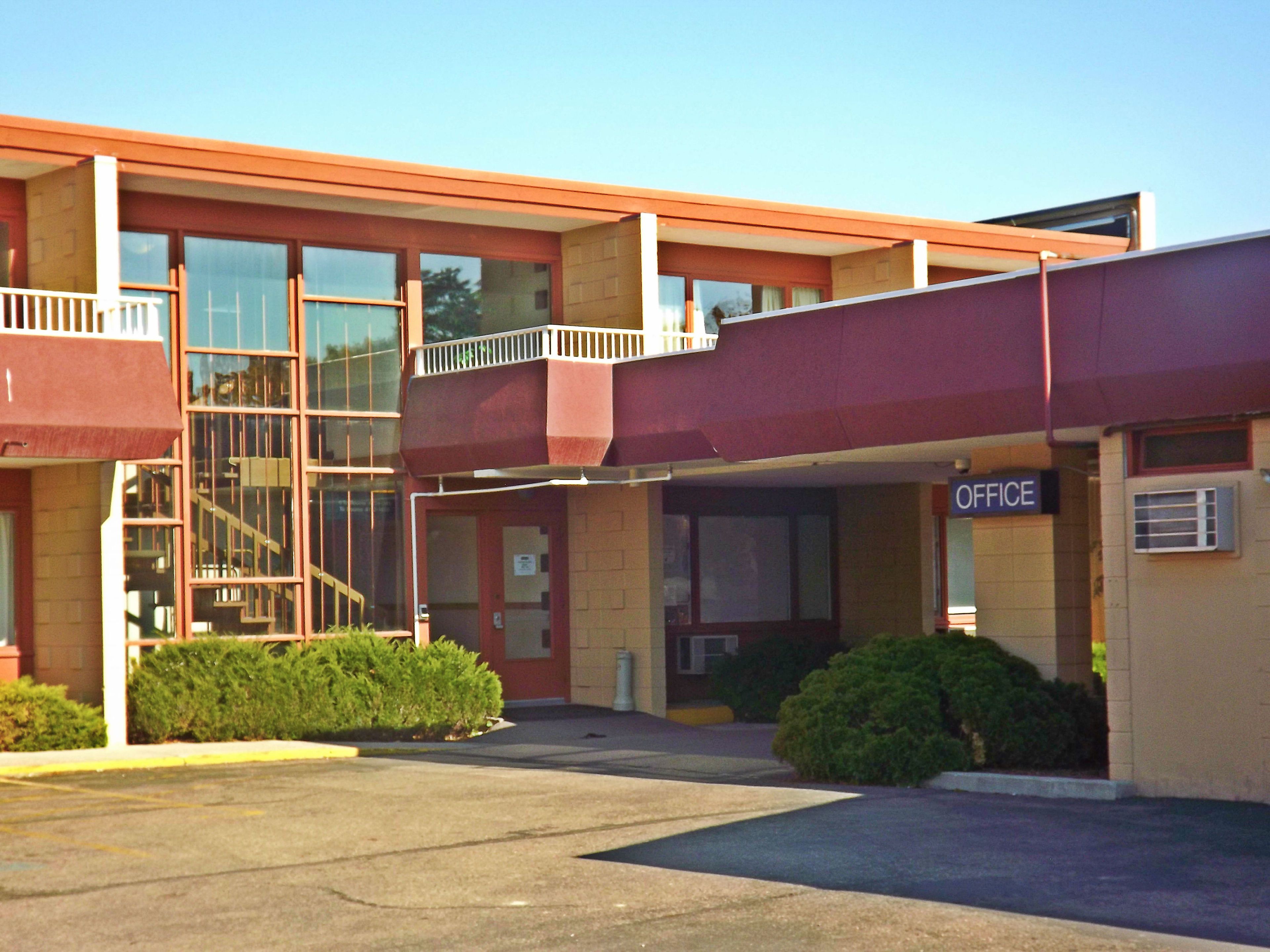 A building with a red exterior, a balcony, and an 'OFFICE' sign.