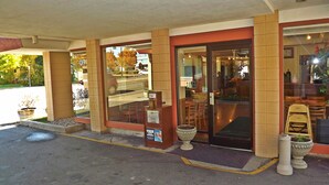 A building with a glass entrance, a tiled facade, and a small outdoor seating area with chairs and tables. - Travelodge by Wyndham Kalispell (Kalispell)