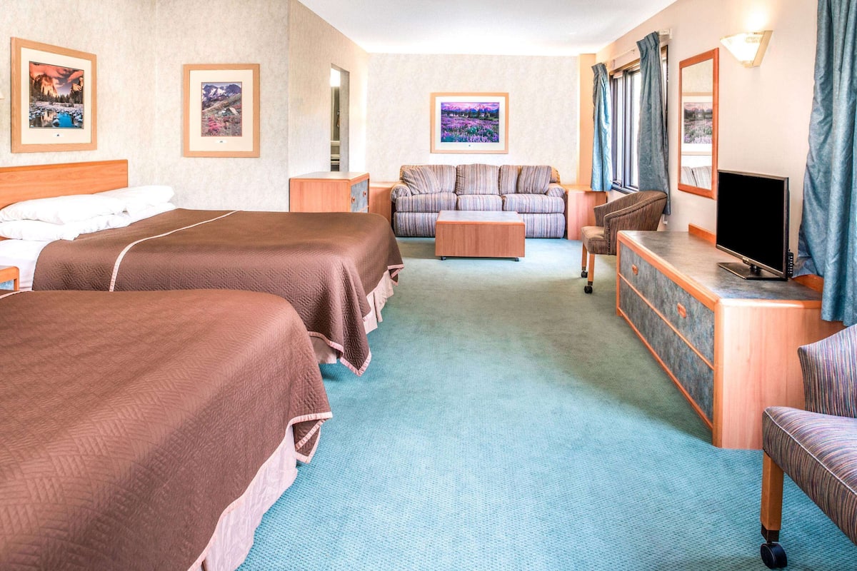Ein Hotelzimmer mit zwei Betten, einer Couch, einem Fernseher und einem Schreibtisch.
