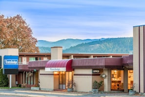 Situated amidst scenic mountains, this hotel offers a simple, functional design with a flat roof and a welcoming entrance.