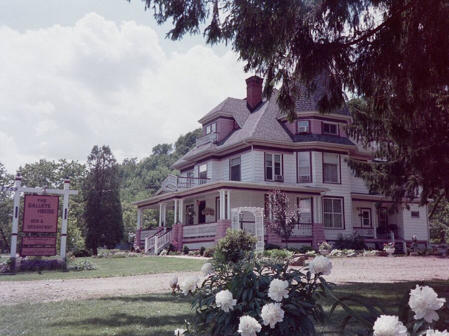 A large, two-story house with a porch and a sign indicating it is a bed and breakfast.
