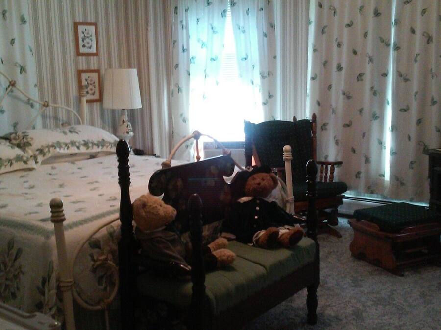 Ein Schlafzimmer mit einem Bett, einem Sessel, einem Fernseher und Stofftieren.